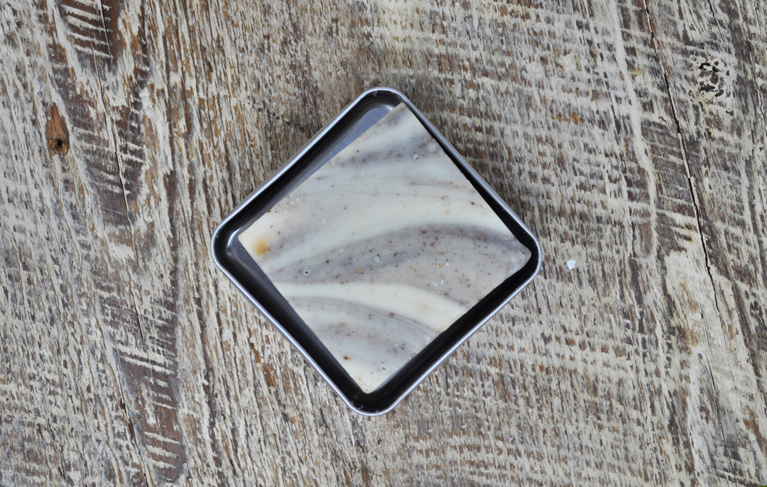An image of a marbled shampoo bar in a metal travel case